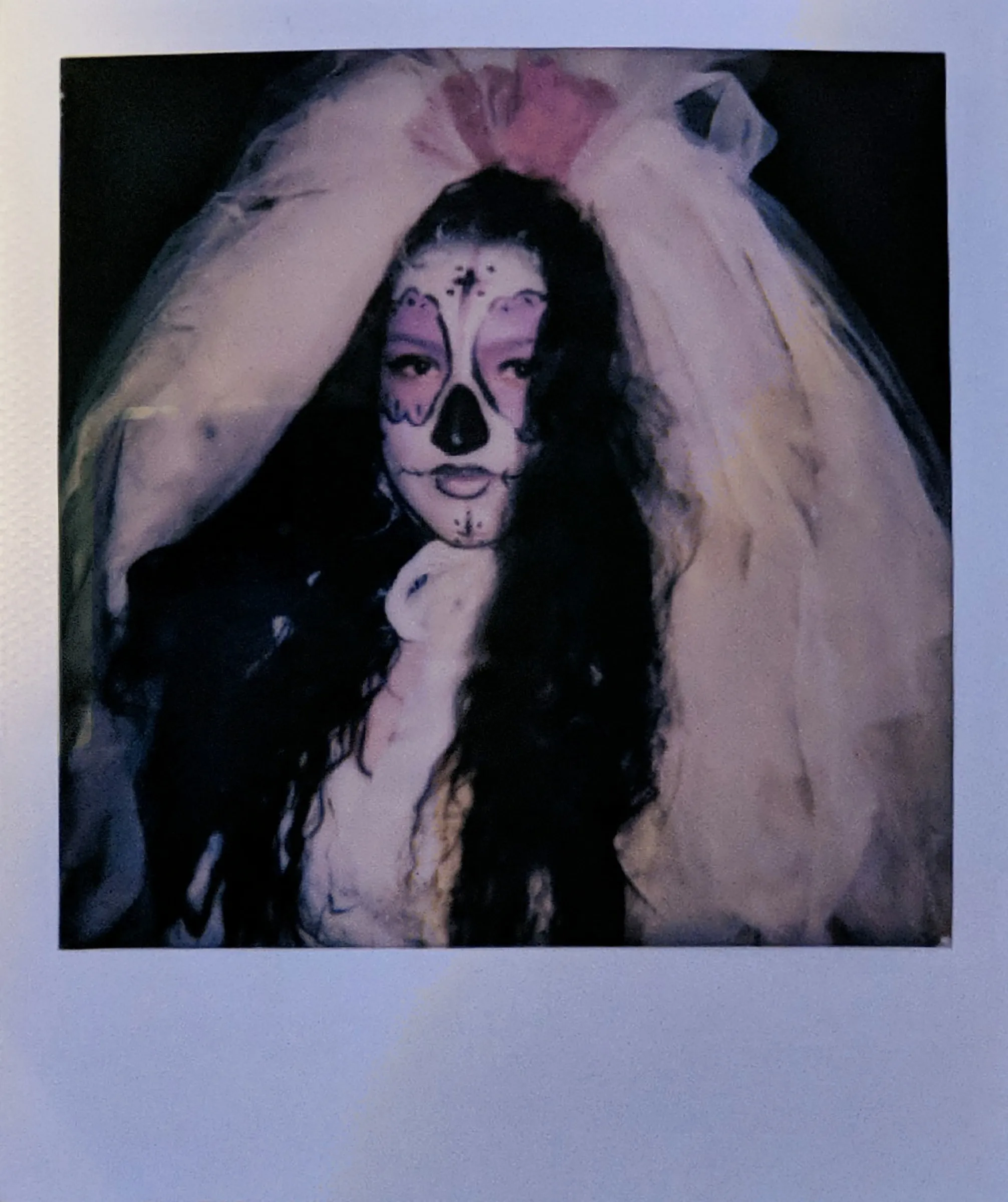 A woman in sugar skull face paint and a white veil, colors shifted to lilac