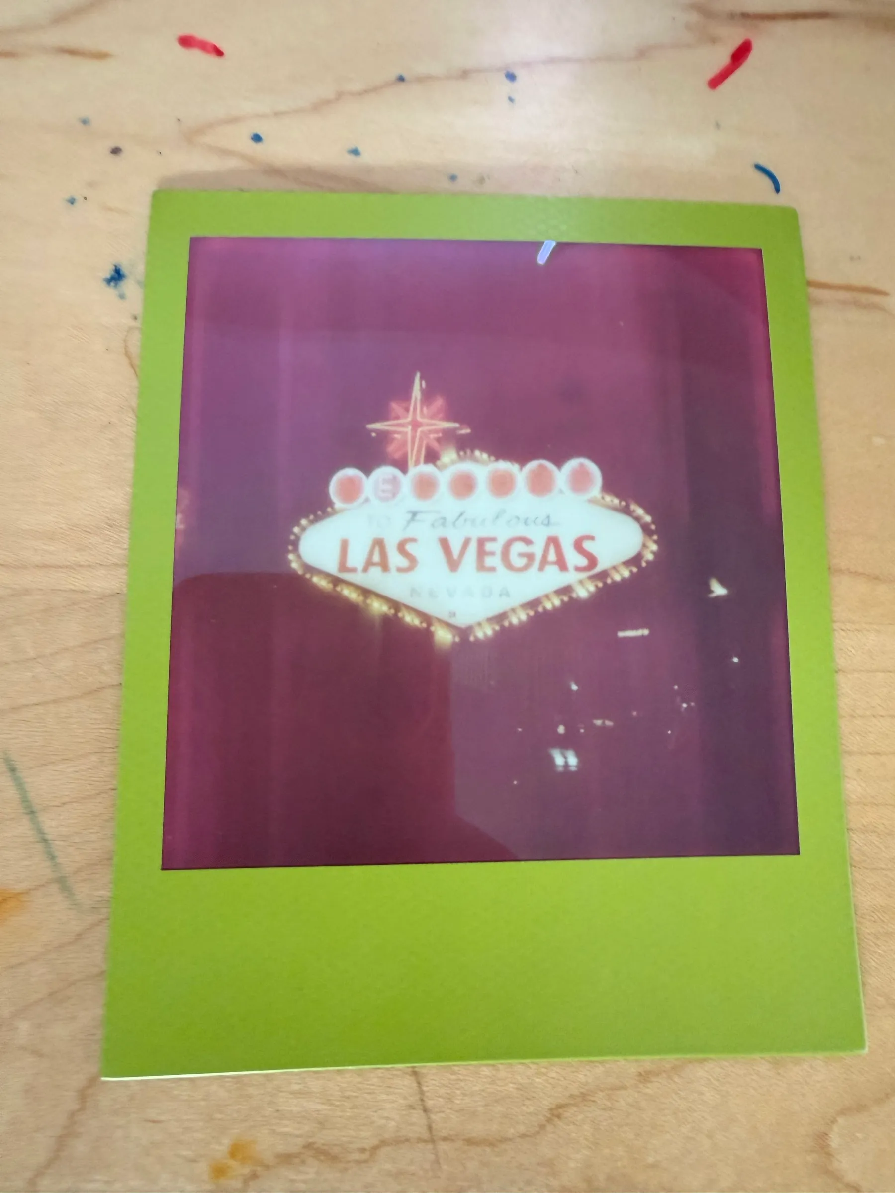 The Las Vegas print photographed on a paint-spattered table, a streak of glare across it