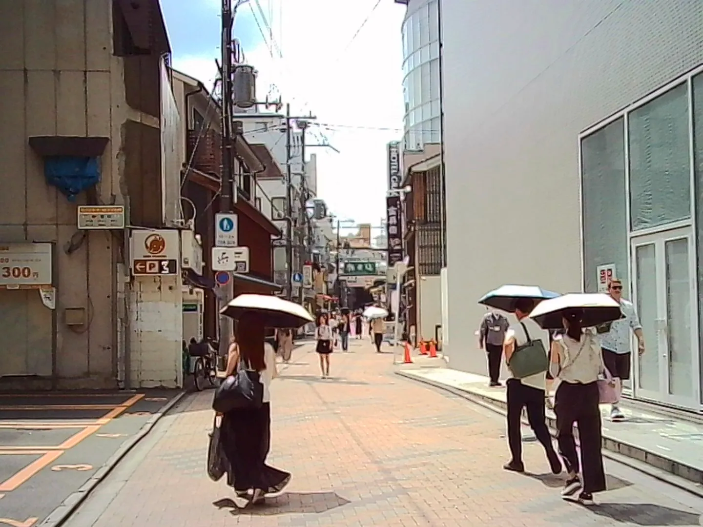 Shoppers with parasols on a hot street, Kyoto