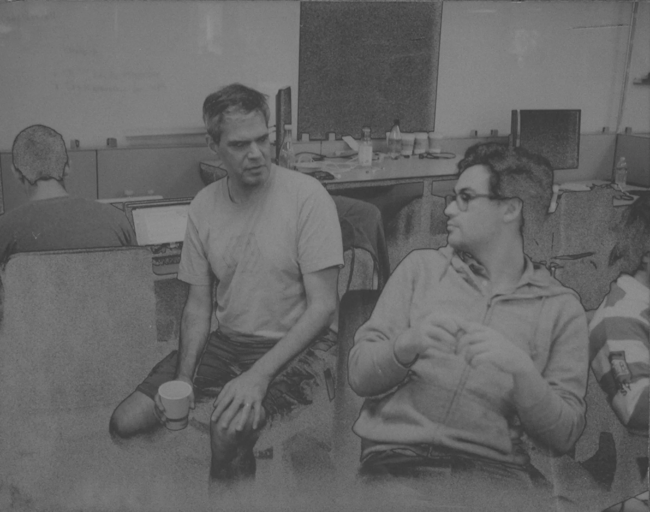 A reclaimed peel-apart negative, stained at the edges, of two people talking in an office